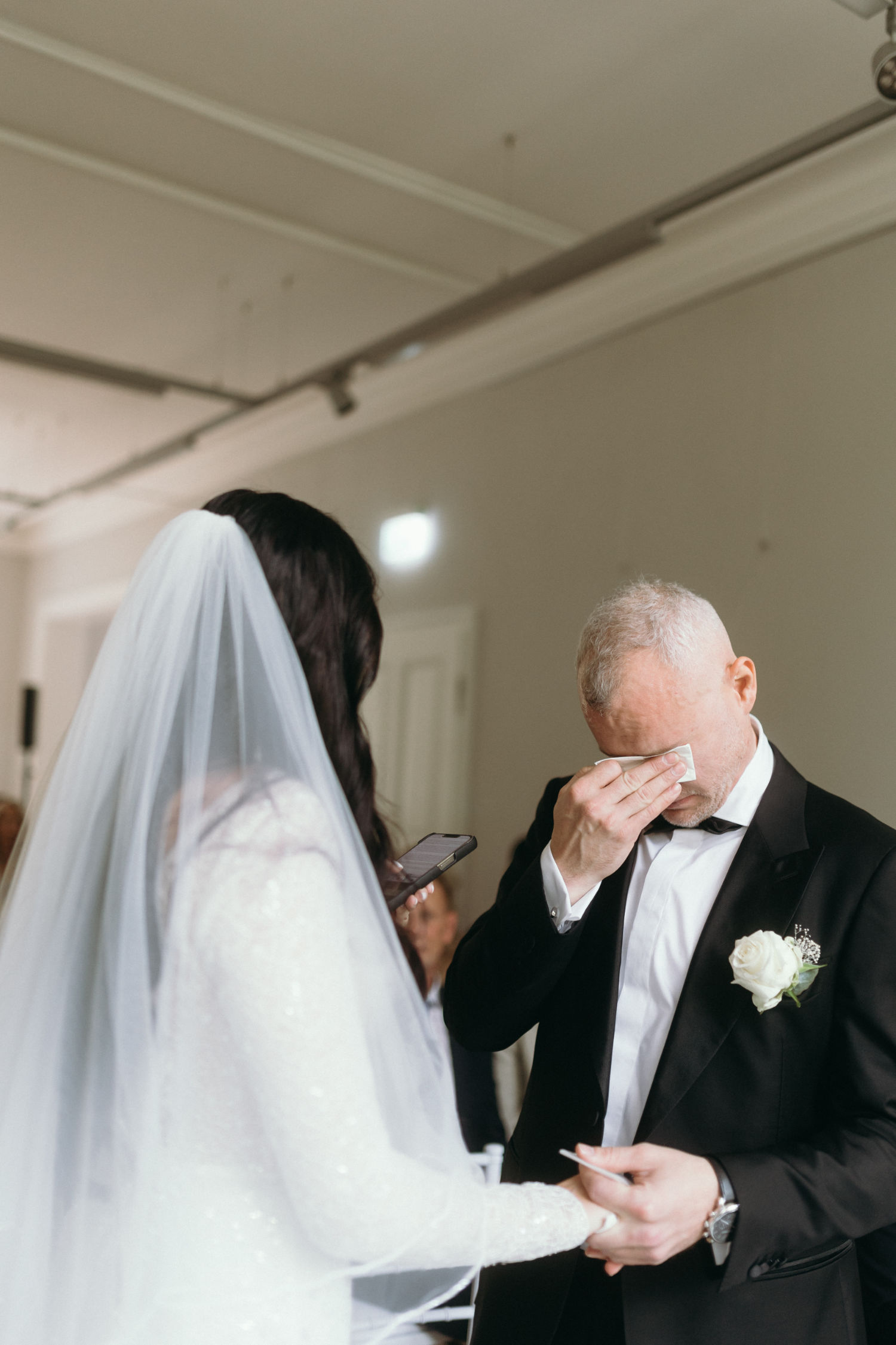 Bride reading vows as groom wipes tears.