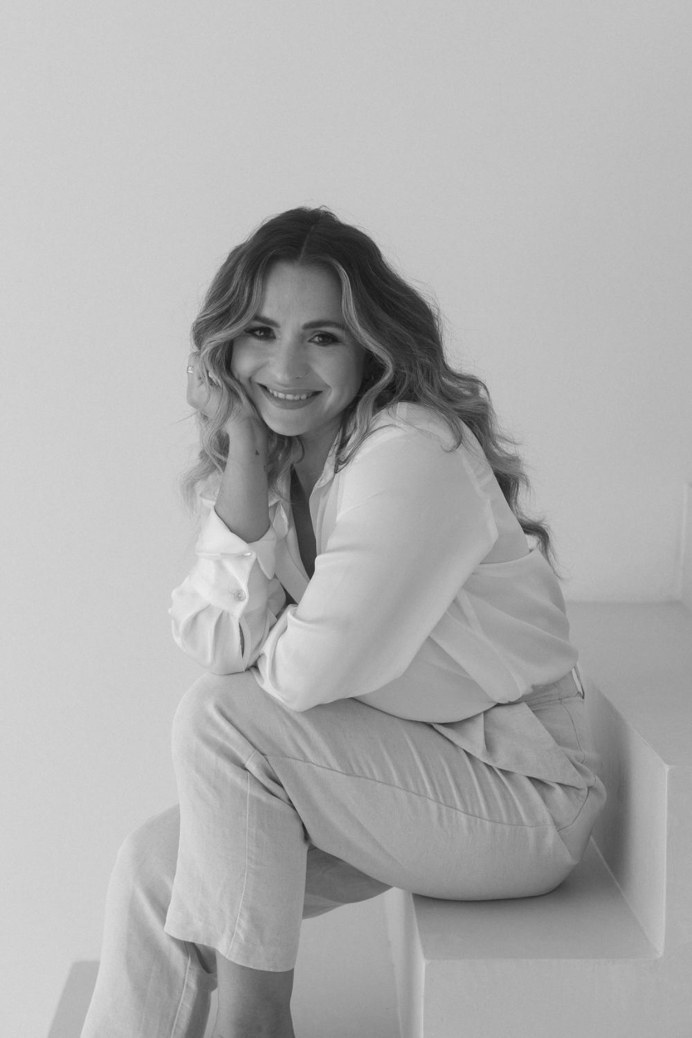 Photographer portrait in black and white, seated on studio steps.