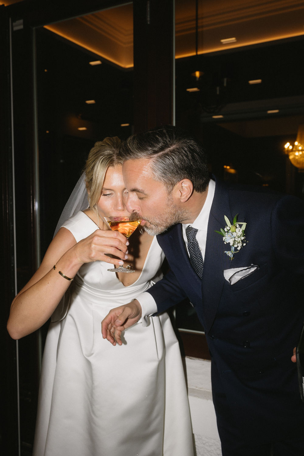 Bride and groom drinking from a single champagne glass.