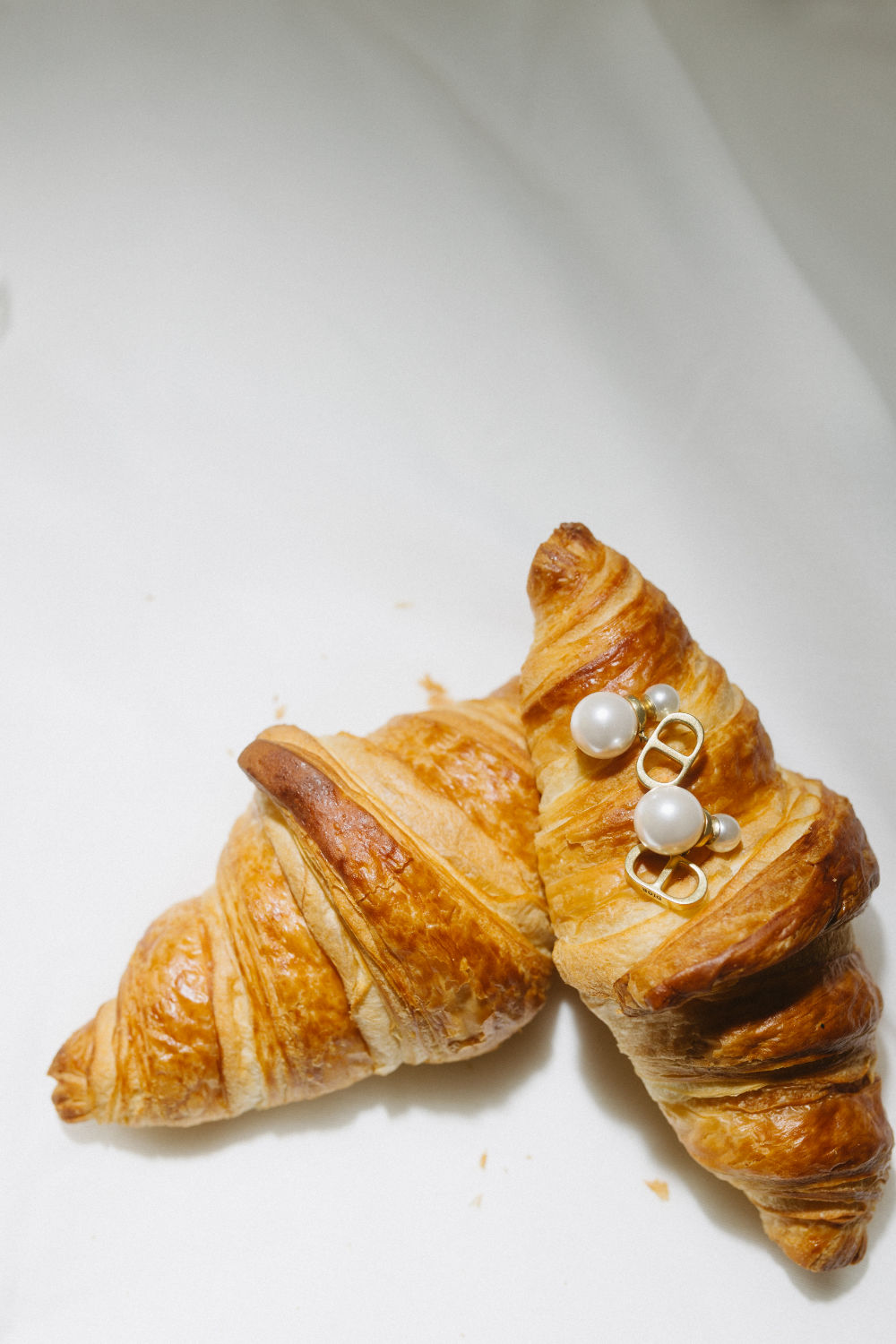 Flashy photo of two croissants adorned with Dior earrings.