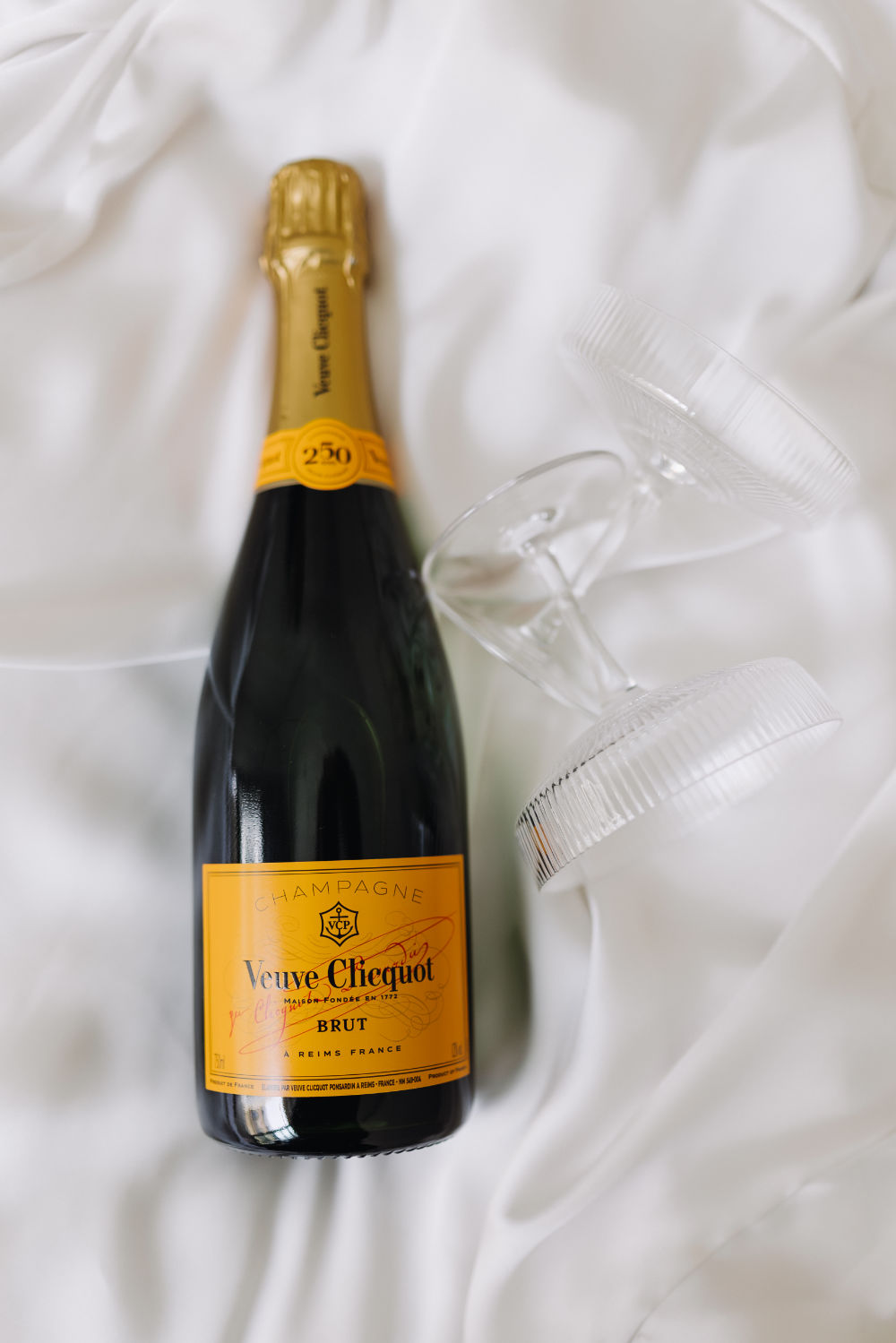 Wedding detail: Veuve Clicquot bottle with two champagne glasses on silk.