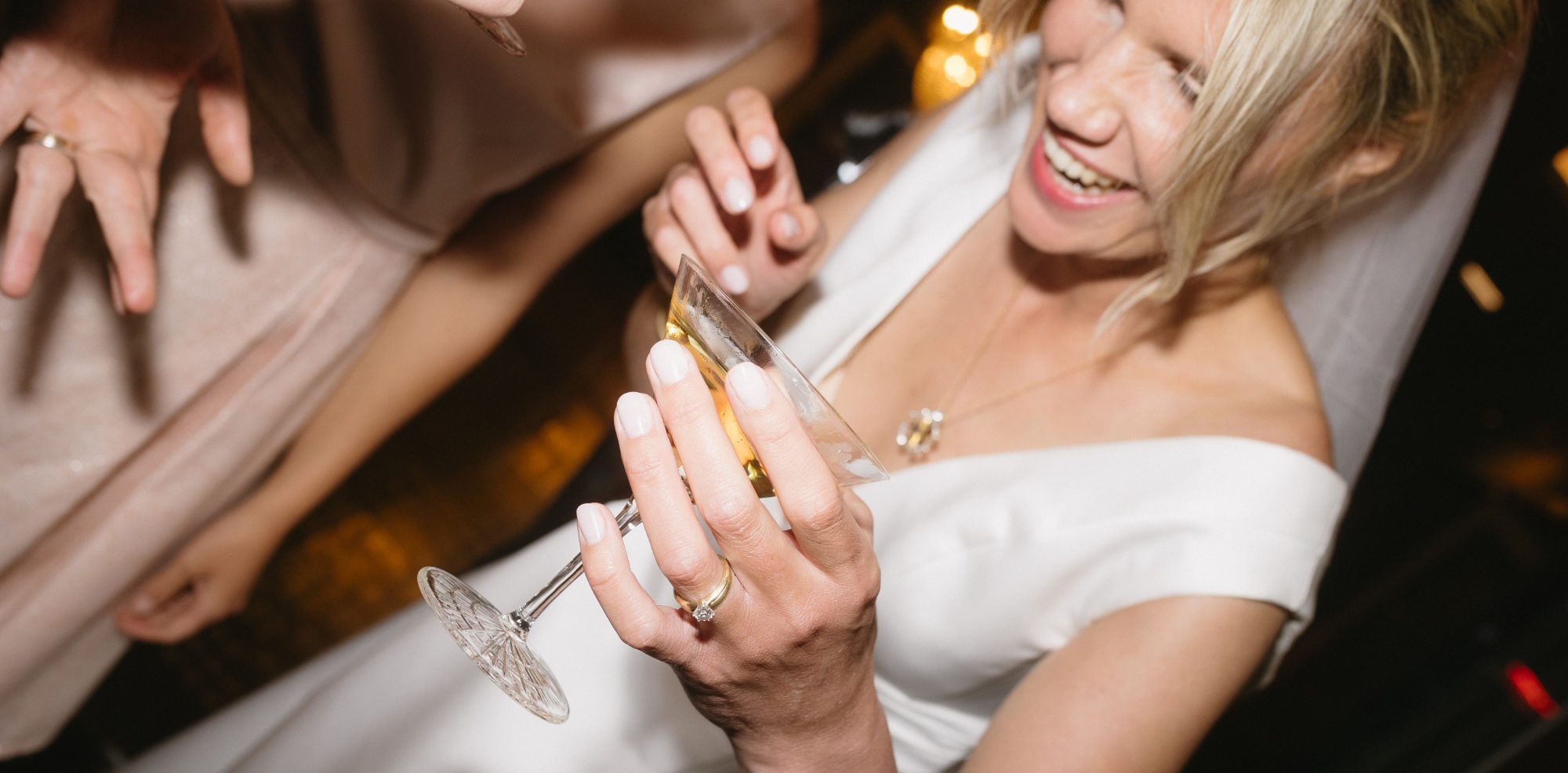 Bride laughing and holding a champagne glass.