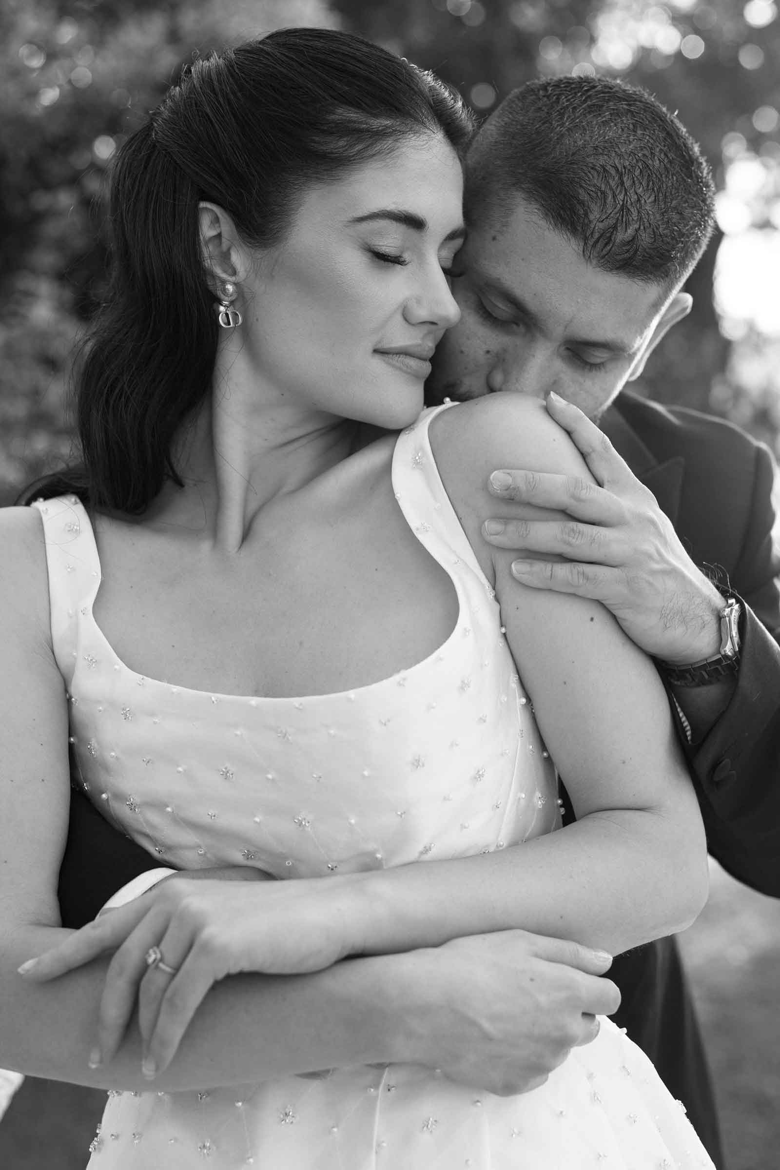 Portrait of bride and groom while groom is kissing the brides shoulder.