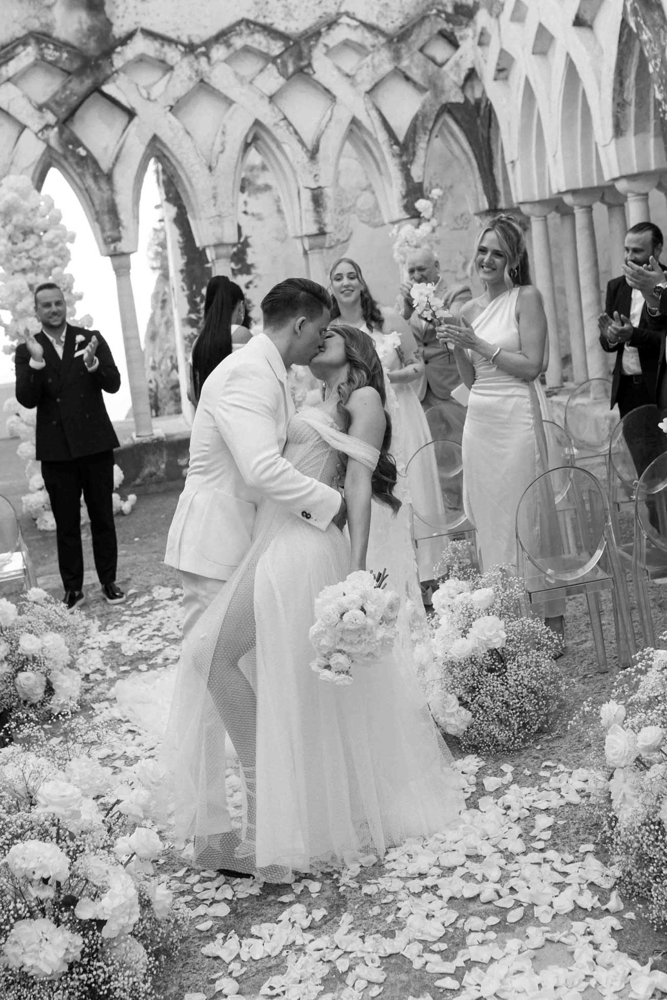 Bride and groom dip kiss while exiting the ceremony.