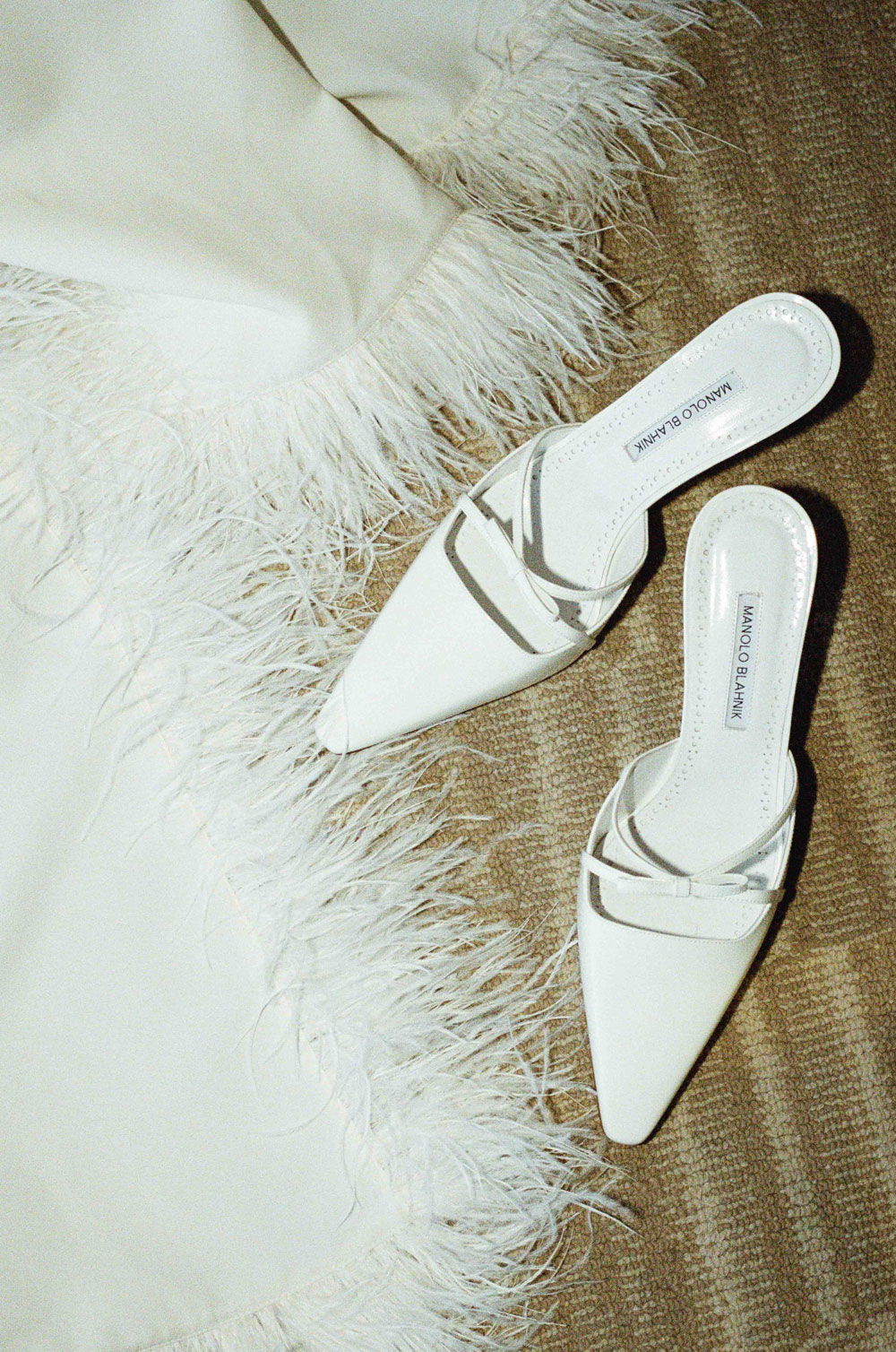 Close-up of Manolo Blahnik bridal shoes next to a feathered dress.
