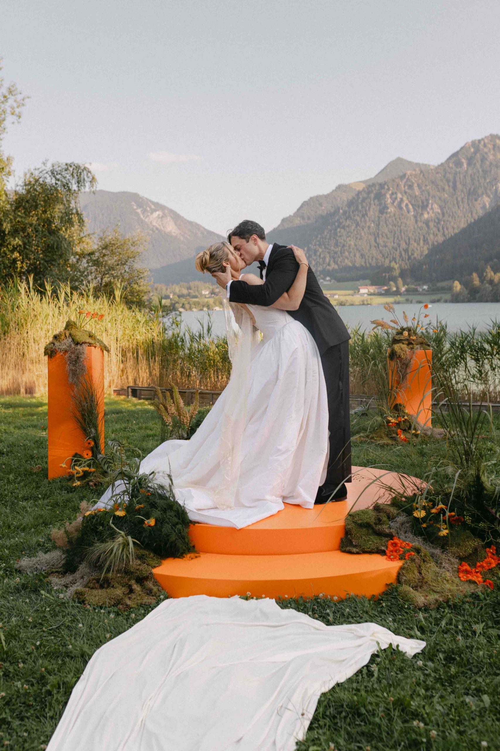  Bride and groom sharing a dip and kiss in front of Lake Tegernsee and the Bavarian Alps.